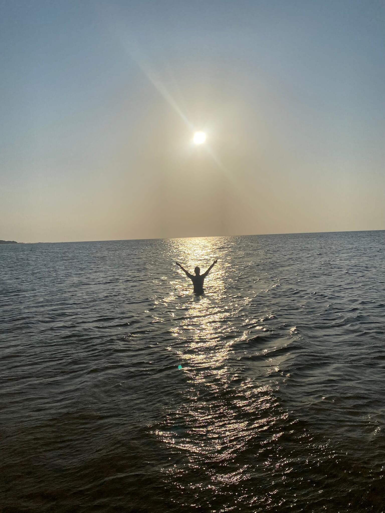Person steht im Rio Tapajós bei Santarém während des Sonnenuntergangs, kein Ufer sichtbar wegen gigantischer Flussbreite