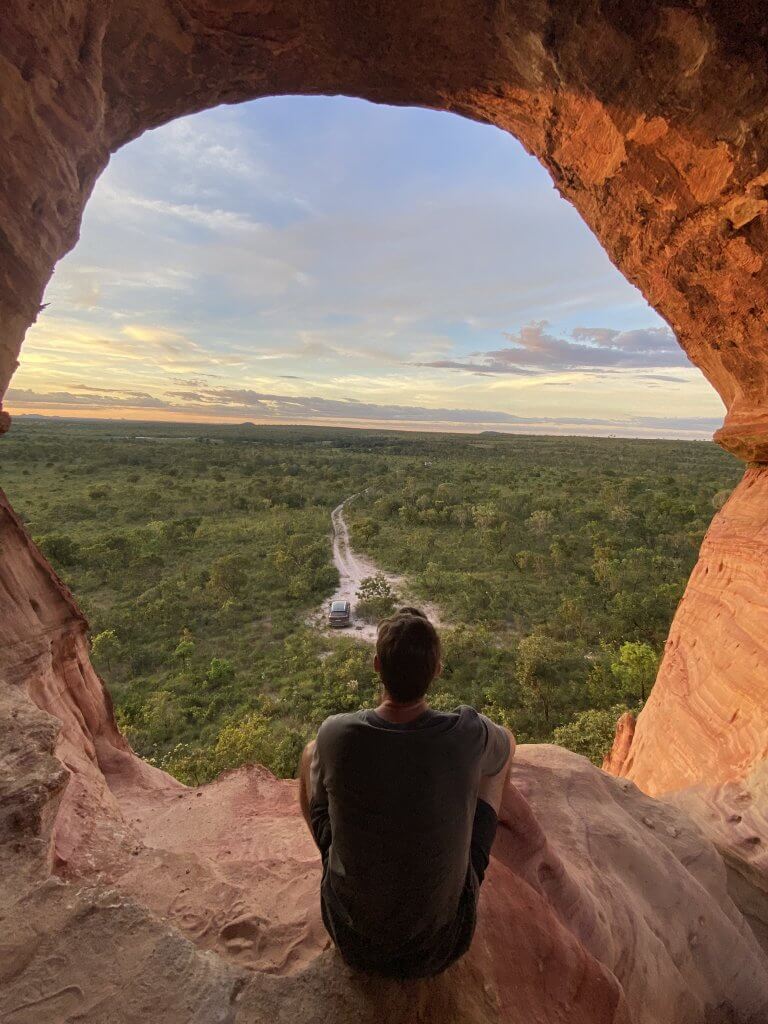 Ich sitzt im Arco do Sol und blickt in den Sonnenuntergang über der Naturkulisse