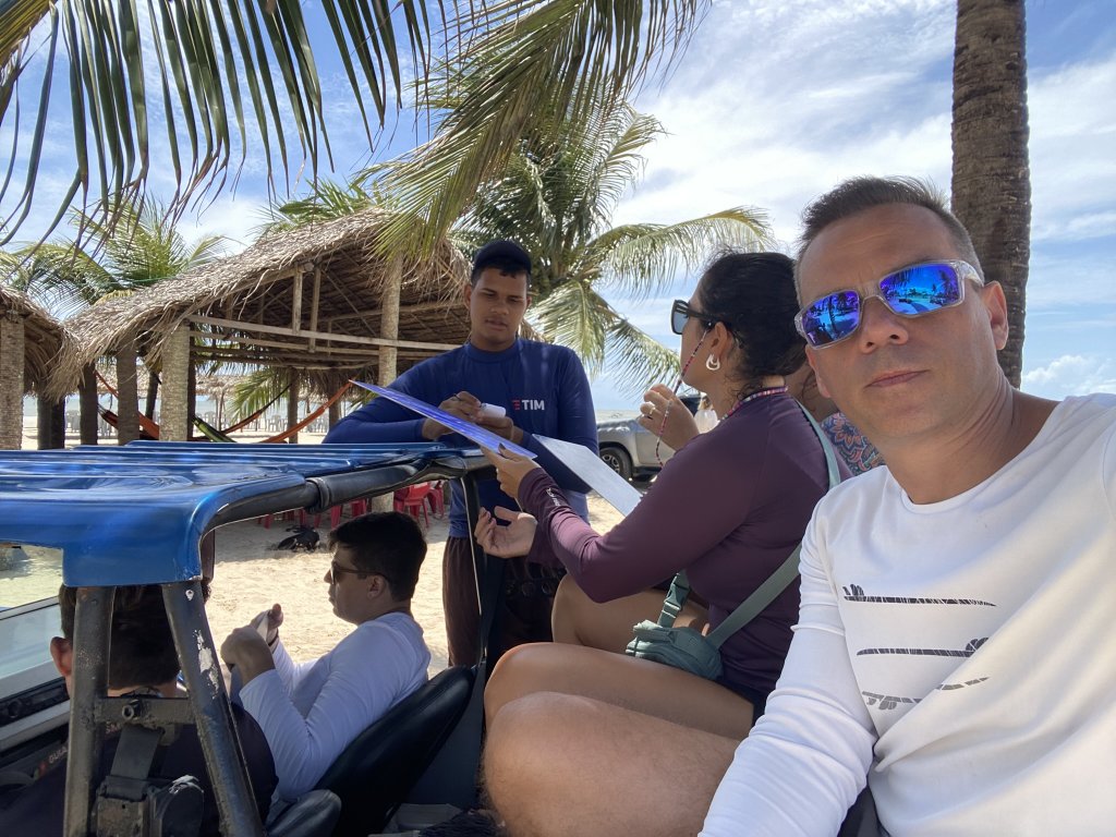 Buggy steht am Strand, während der Kellner einer Strandbar die Bestellung direkt ans Fahrzeug aufnimmt