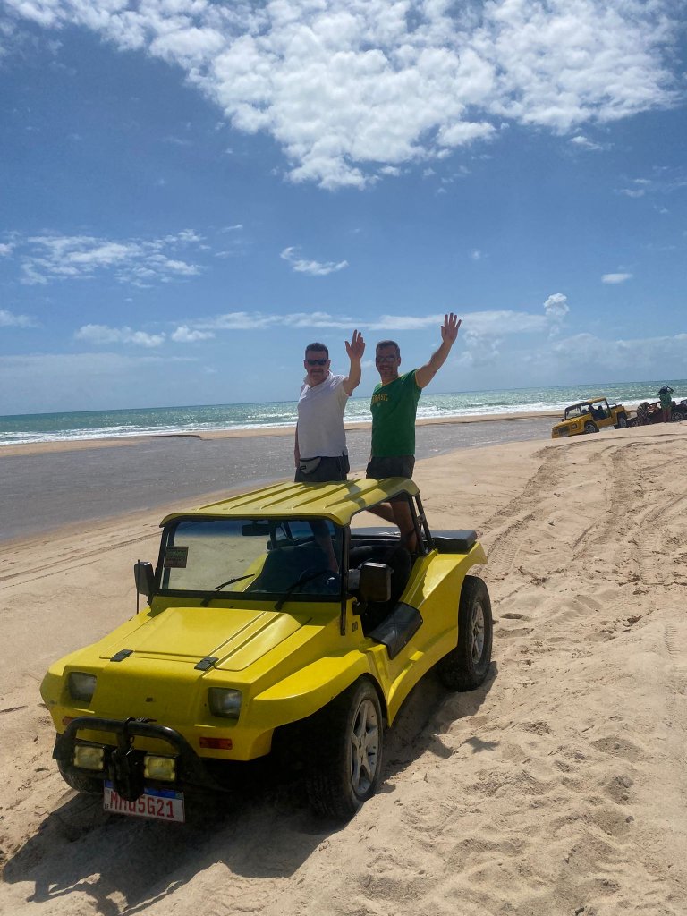 Gringo und Arne stehen auf dem gelben Buggy am Strand von Barra de Gramame, im Hintergrund fließt der Fluss ins Meer