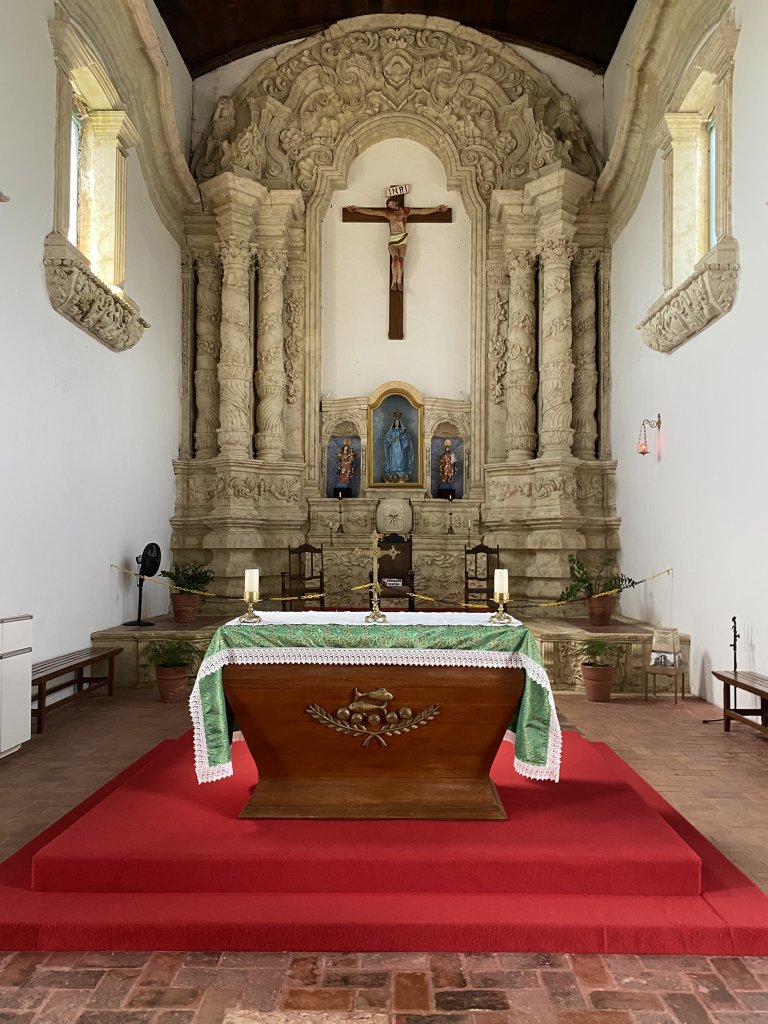 Barocker Steinaltar mit kunstvollen Bögen und Säulen, davor ein hölzerner Altartisch auf rotem Podest in der Kirche Nossa Senhora da Guia