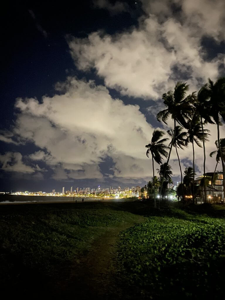 Strand von João Pessoa bei Nacht mit Skyline und beleuchteten Wolken