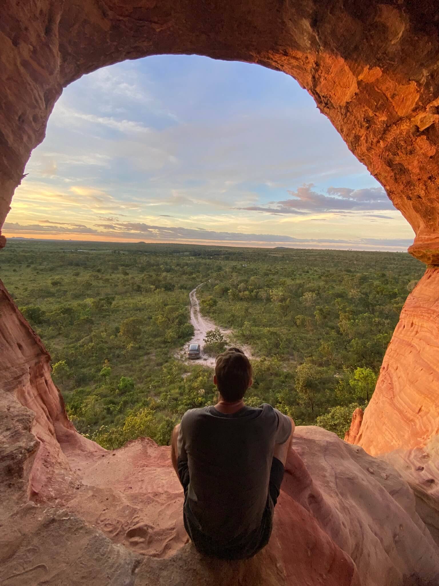 Ich sitzt im Arco do Sol und blickt in den Sonnenuntergang über der Naturkulisse