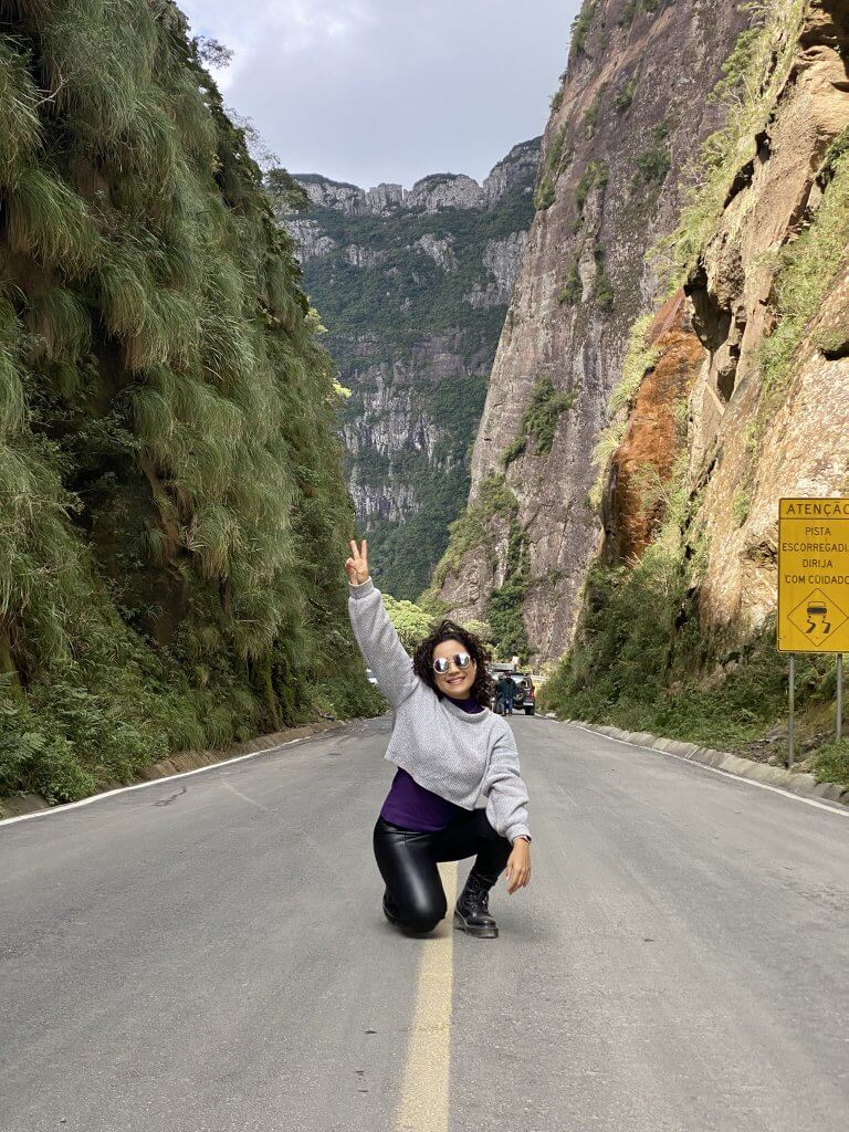 Lívia kniet auf der Straße im künstlichen Canyon der Serra do Corvo Branco in Urubici und streckt eine Hand nach oben