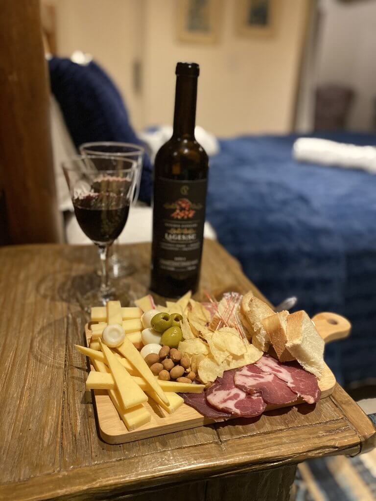 Käse- und Wurstplatte mit zwei Gläsern Wein im Hotelzimmer in Urubici